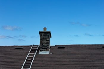 Chimney with a ladder set up for service, similar to homes throughout Cleveland, OH